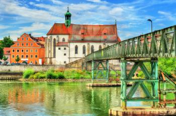 St. Oswald Church with Eiserner Steg bridge across the Danube River in Regensburg - Germany