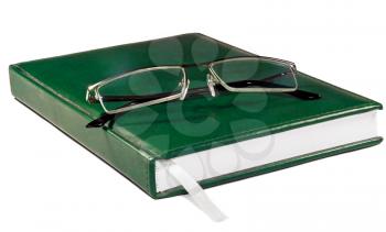 Glasses on the the Green Book isolated on white background