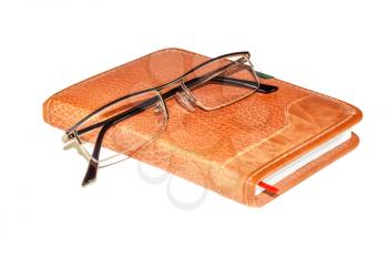 Glasses on a notebook isolated on white background