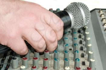 Hand with a microphone on the audio mixer