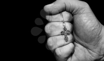Black and white image of a hand with a cross on a dark background