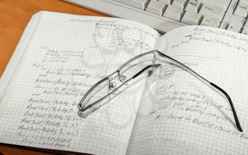Notebook with glasses and a computer keyboard close-up