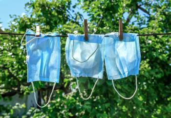 Three used washing face masks drying on a sunny day