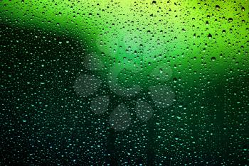 Bright water droplets on glass. Green lights.