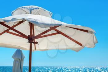 Big white parasol on a background of bright blue sky close-up. Beach umbrella.