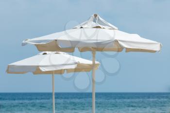 Two white beach umbrella on a background of sea and sky. Shallow depth of field.
