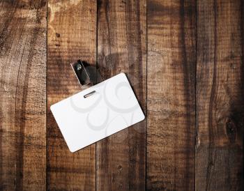 Blank badge. Blank plastic id card on vintage wooden table background. Blank white plastic badge. Mock-up for branding identity. Top view.