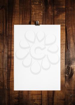 Blank sheet of paper on vintage wooden table background. White paper with plenty of copy space. Blank paperwork template for design portfolios. Top view.