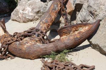 A large fragment of old weathered rusty ship anchor