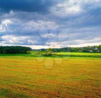 Grass field and dramatic sky with rain clouds. Rural landscape.