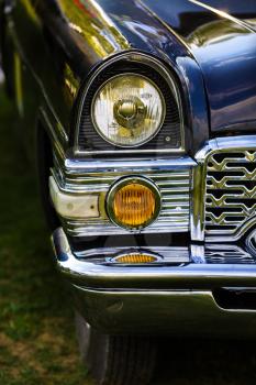 Close-up of the headlights and the front part of an old black retro car. Classic vintage retro car. Selective focus on the car's headlight.
