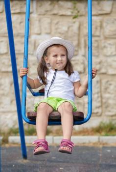 Child playing with a swing. Outdoor portrait of a cute baby girl.