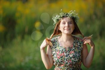 Smiling girl with a wreath keeps his hair. Sunset light. Space for text. Shallow depth of field. Focus on eyes.