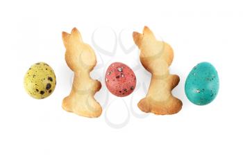 Multicolored painted quail eggs and biscuits in the shape of rabbits on a white background. Isolated with clipping path.