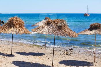 Straw beach umbrellas against the blue sea on a sunny summer day.