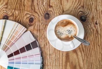 Color palette guide and coffee cup on wood table background. Sample colors catalog.