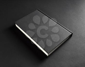 Photo of blank black book cover on black paper background.