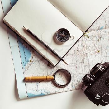 Preparation for travel. Map, notepad, camera, magnifier, compass, pencil and glasses. Vintage toned image. Top view. Flat lay.