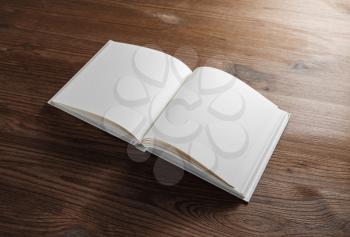 Blank open book or notebook on wood table background. Responsive design mockup.