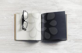 Blank open book and glasses on wood table background. Responsive design mockup.