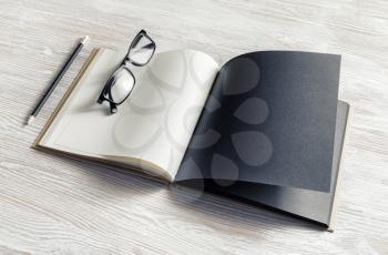 Mockup of opened blank booklet, pencil and glasses on light wooden background.
