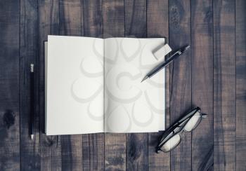 Opened blank notebook, glasses, pencil and eraser. Stationery on vintage wood table background. Flat lay.