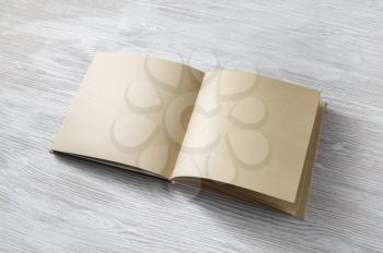 Blank notepad or book of kraft paper on light wooden background. Mockup for your design.