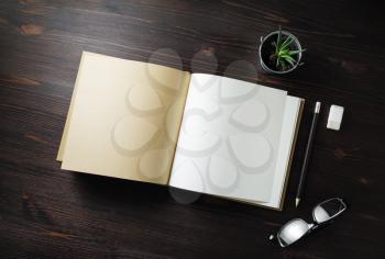 Blank open book, stationery and plant on light wooden background. Flat lay.