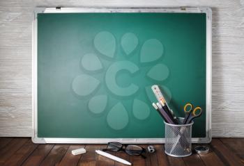 School stationery over green chalkboard background. Education concept.