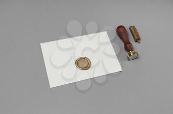 Blank envelope with wax seal and stamp on gray paper background.