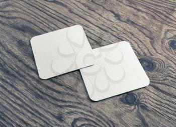 Photo of two blank white beer coasters on wood table background. Blank template for your design.