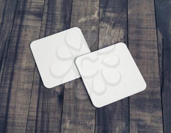 Two blank white beer coasters on wooden table background. Responsive design mockup.