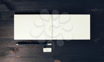 Photo of open sketchbook with blank pages, pencil and eraser on wooden background. Responsive design template. Flat lay.