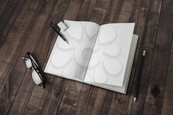Blank open book and stationery on wood table background. Responsive design mockup.