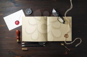 Photo of book with blank kraft paper pages and vintage stationery on wooden background. Flat lay.