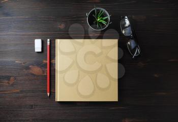 Blank book and stationery on wooden background. Notepad, glasses, pencil, eraser and plant. Flat lay.