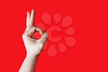 Female hand shows gesture OK over red background. Hand ok sign.