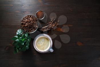 Delicious fresh coffee. Coffee cup, coffee beans, plant and ground powder on vintage wood table background. Top view. Flat lay.