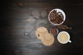 Still life with hot coffee cup, coffee beans, beer coasters and ground powder on wood kitchen table background. Lot of copy space for your text. Flat lay.