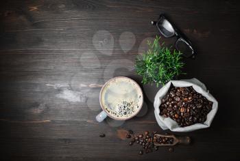 Vintage coffee background, Coffee cup, glasses, plant and roasted coffee beans in canvas bag on wood kitchen table. Flat lay.