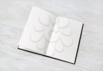 Opened booklet with blank white pages on light wooden background. Space for text.