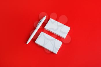 Branding stationery mockup on red paper background. Blank objects for placing your design. Blank business cards and pen.
