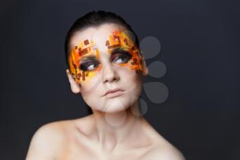 Portrait of a girl with an original make-up. Beauty close-up. Orange and red rhinestones on a face
