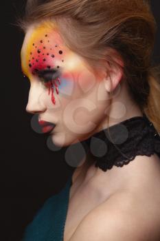 Portrait of young and beauty female model with creative makeup, bloody eyes and black rhinestones