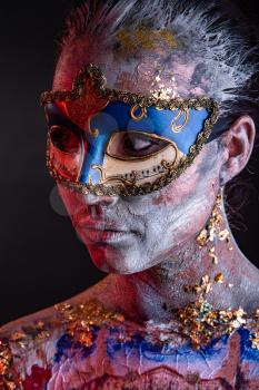 Portrait of a young masked woman with creative makeup on the theme of Venice Carnival
