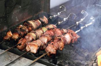 Slices of meat with onion preparing on fire (shish kebab)