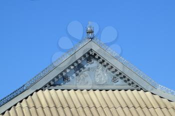 Decorative elements on the ridge of the roof. The roof of slate and horse of the decorative sheet. Lions and flowers from the sheet metal on the front.