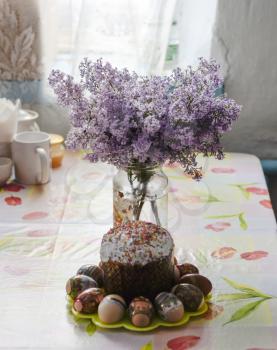 Bouquet of lilacs near Easter cakes and colored eggs