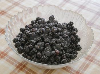 Plate with berries black blackberries. Fruits berries on the table.