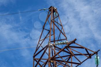 Supports high-voltage power lines against the blue sky with clouds. Electrical industry.